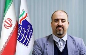 وحید یزدانیان در کنار پرچم ایران و پرچم سازمان فضایی